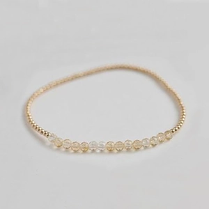 Close-up of handmade elastic bracelet featuring gold beads and faceted amethyst crystals