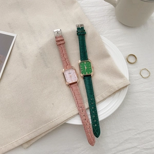Detail of rectangular women's watches in pink and green with crocodile texture leather straps