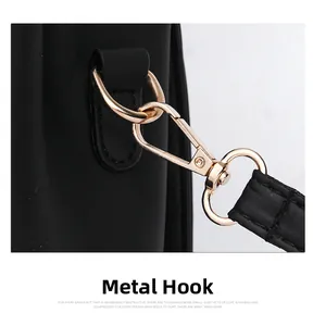 Detail of light gold lobster clasp and D-ring on black leather crossbody bag