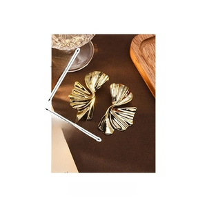 Detailed view of gold leaf earrings with dimensions 6cm by 3.6cm on a leather texture