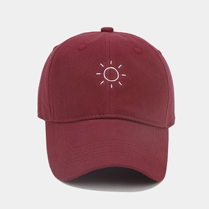 Detailed embroidery of white sun motif on burgundy cotton baseball cap front