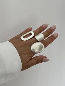 Close-up of minimalist matte silver rings featuring brushed texture and geometric shapes