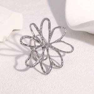 Détail macro d'une bague fleur évidée minimaliste en argent sur fond blanc pur