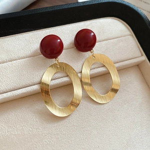 Macro shot of red resin beads and oval brushed gold metal earrings in a velvet case