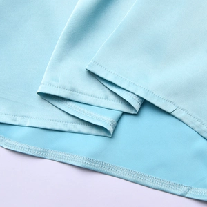 Dettaglio del tessuto in seta azzurro che mostra la texture liscia e la cucitura dell'orlo