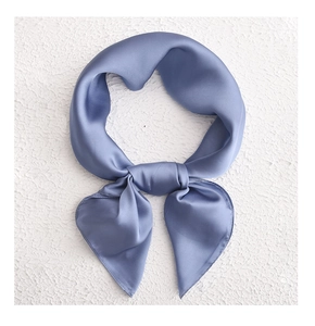 Close-up of a knotted grey-blue silk scarf showing smooth texture on white background