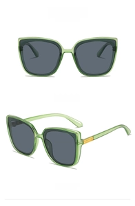 Detail of square cat-eye sunglasses in transparent green with gold metal accents