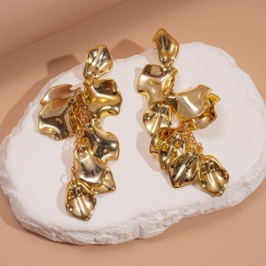 Macro shot of gold metallic petal drop earrings with polished surface on stone