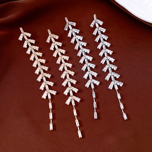 Detailed view of leaf tassel drop earrings with sparkling zircon on dark silk fabric
