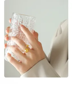 Détail d'une bague ouverte dorée avec deux perles polies portée par un mannequin