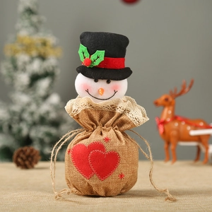 Detail of Christmas burlap gift bag with red hearts, lace trim, and snowman head decoration