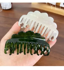 Detail of cream white and dark green wavy acetate claw clips for thick hair