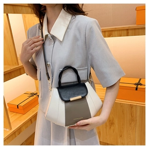 Detail of color-block PU leather handbag with gold hardware held by a model