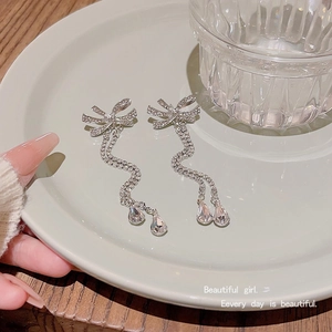 Detail of silver bow tassel earrings with sparkling zircons and water drop pendants