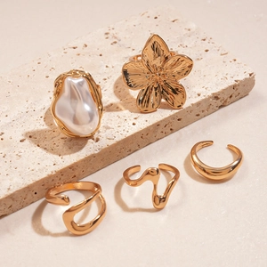 Detailansicht eines 5-teiligen goldenen Ring-Sets mit Kunstperlen und floralen Mustern