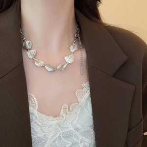 Dettaglio della collana con perle barocche e catena d'argento indossata da una modella