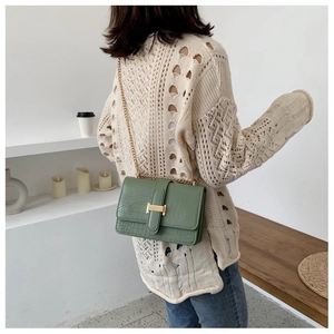 Close-up of green crocodile texture shoulder bag with gold H-shaped metal buckle