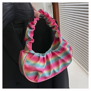 Detail of colorful rainbow gradient pleated bag with satin texture held by a model