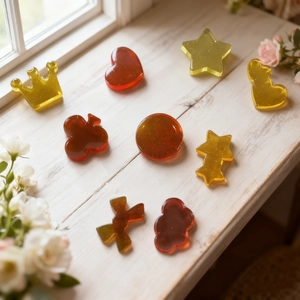 Dettaglio di ciondoli in resina ambra a forma di cuore, stella e fiore con glitter fini