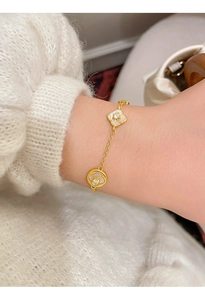 Dettaglio di bracciale a fiori placcato oro 18K con madreperla e zircone al polso