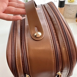 Brown faux leather cosmetic bag with top handle and multi-zipper compartments for travel