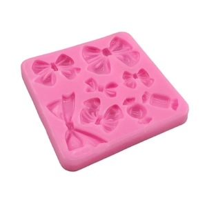 Pink silicone mold featuring multiple bow and candy shapes for cake and fondant baking