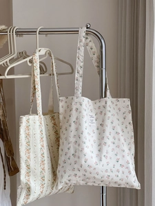 Detailed view of floral canvas tote bags with delicate orange and purple prints