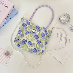 Detail of floral tote bag with purple rope handles and elegant pearl shoulder strap