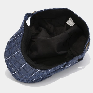 Détail de la casquette plate à carreaux montrant la doublure et la boucle métallique