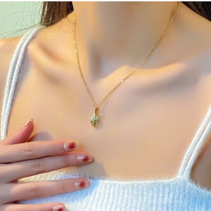 Close-up of golden leaf pendant necklace on model with soft lighting and elegant detail