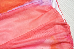Détail du tissu en maille fine avec dégradé rose et orange et bords ourlés de qualité