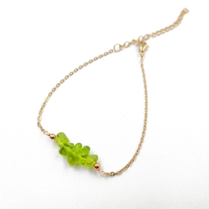 Detail of adjustable gold chain bracelet with irregular olive green crystal stones