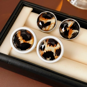 Close-up of leopard print faceted earrings with gold and silver rims in a jewelry box