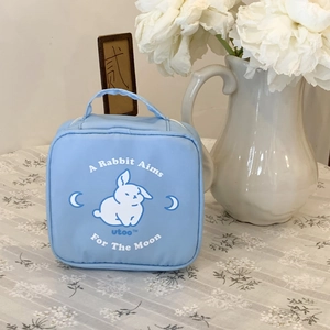 Close-up of a light blue square cosmetic bag featuring a white rabbit and moon design