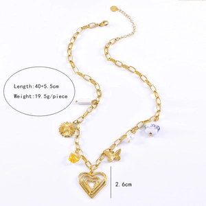 Detail view of multi-element gold necklace with pearl, butterfly, and heart charms