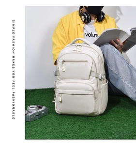 Detail of beige travel backpack with multiple compartments shown in an outdoor lifestyle setting