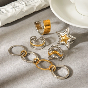 Detail of five mixed-metal rings including star, chain and hammered band on grey felt