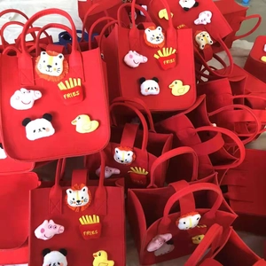 Macro detail of red felt gift bags with 3D cartoon animal patches and handle