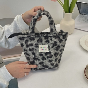Detail of plush leopard print handbag showing the woven logo label and zipper closure