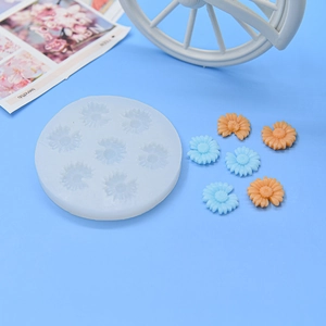 Detail of daisy silicone mold with colorful flower resin crafts on a light blue background