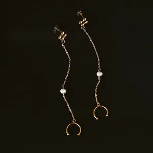 Elegant gold plated titanium steel clover tassel pearl earrings on brown textured background