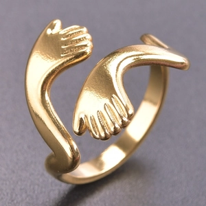Macro shot of gold hugging hands open ring in stainless steel with polished finish
