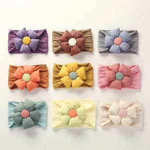Flat lay of nine soft jacquard nylon baby headbands with large flowers in diverse colors