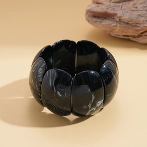 Macro shot of chunky marble resin bracelet with geometric segments on warm stone background