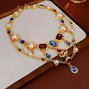 Macro shot of vintage gold layered necklace with red blue gemstones and white pearls