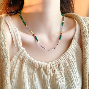 Detailed close-up of a vintage-style beaded necklace featuring green and purple stones