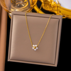 Detail of a gold flower pendant with six white pearls displayed on a brown jewelry box