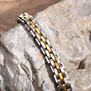 Close-up of gold and silver steel watch-band bracelet on a grey stone background