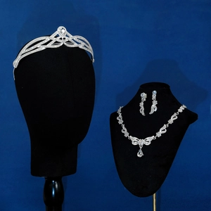 Close-up of a silver bridal jewelry set with crown necklace and earrings on a model