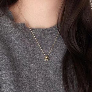 Detailed close-up of a golden flower pendant necklace with a black center on neck